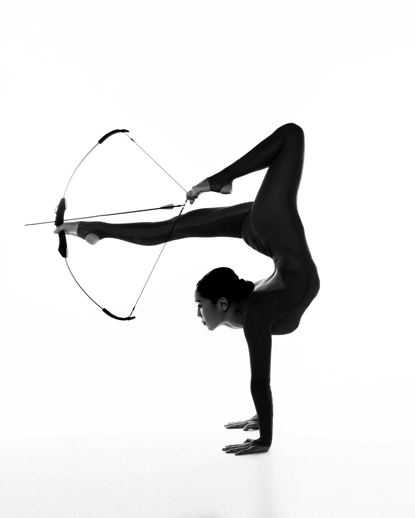 Nyamgerel in a one-arm handstand drawing a bow with her feet